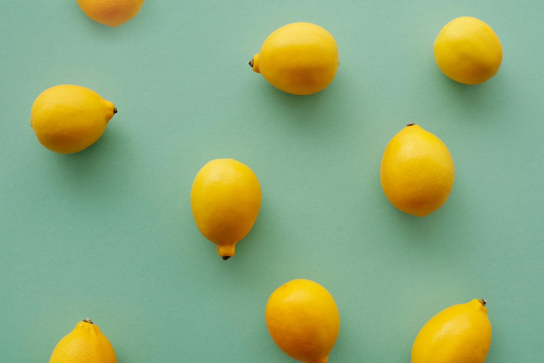 Bright yellow lemons arranged on a pastel green background, representing fresh sensation and careful introduction