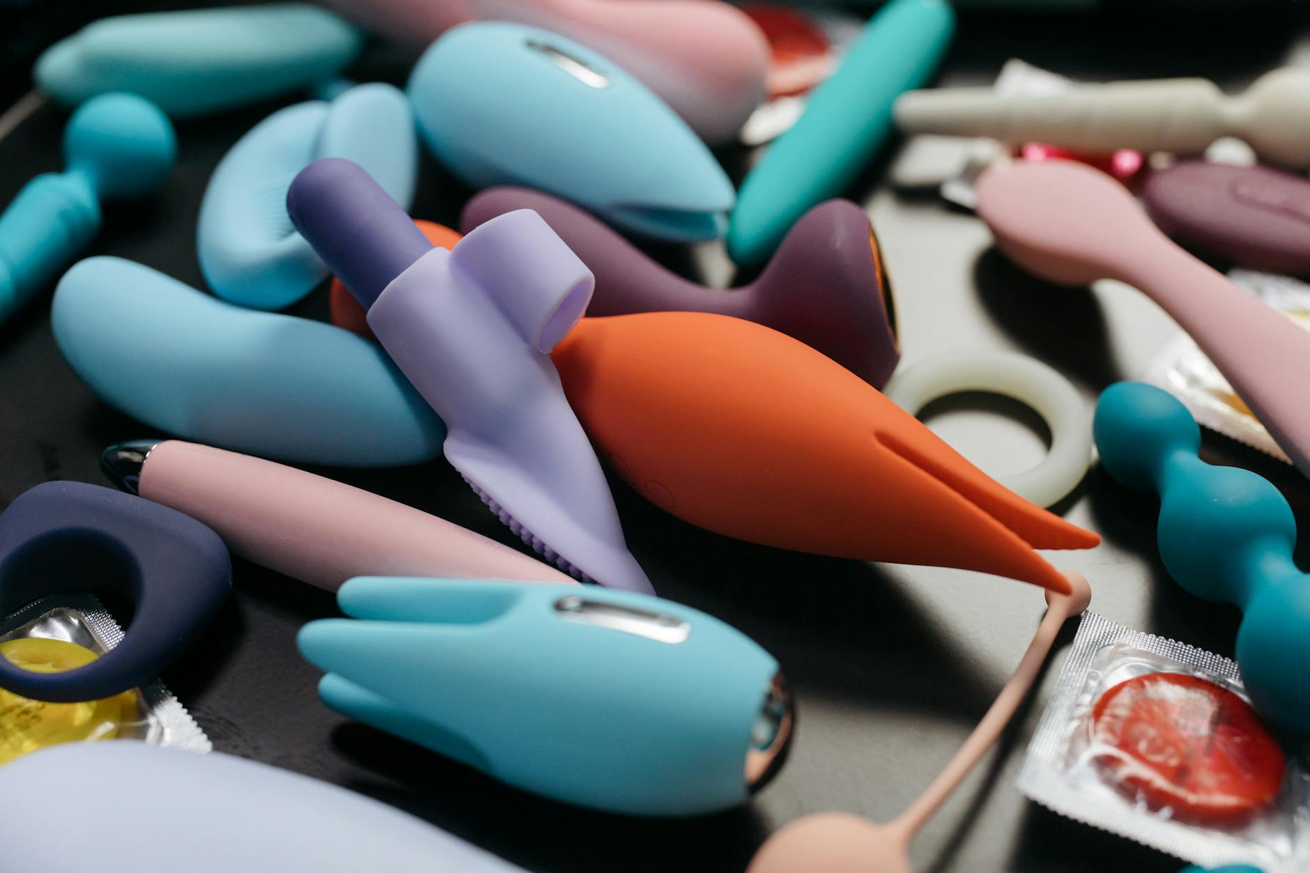 Intimate close-up of hands holding a sleek blue vibrator against a purple background