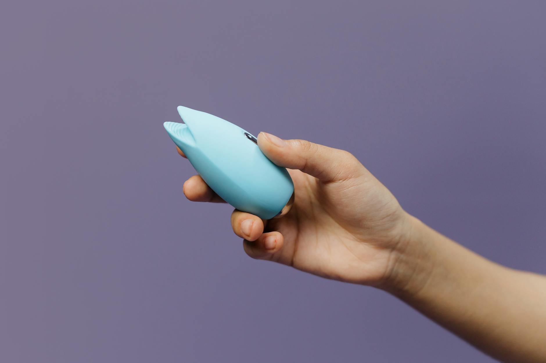 A vibrator held against a purple background, representing self-pleasure and sexual wellness for adults over 40