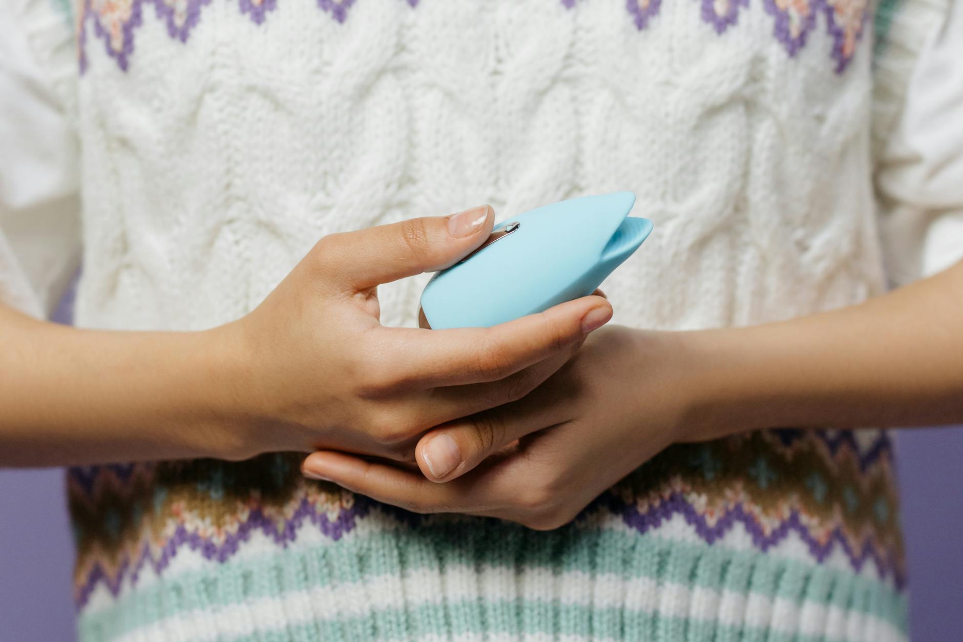 Woman holding blue and pink silicone vibrators in contemplative pose