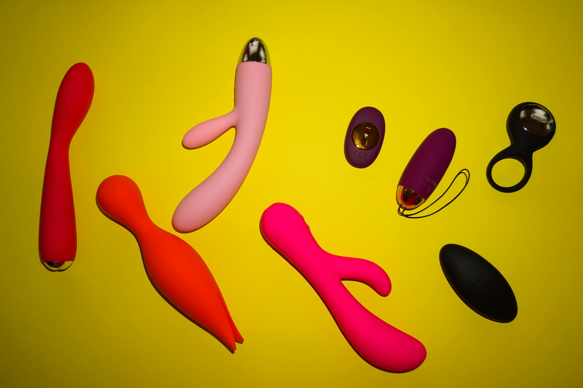Vibrant display of colorful clitoral vibrators including lemon suction toys arranged on a bright yellow surface
